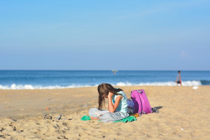 girl and schoolbag on beach